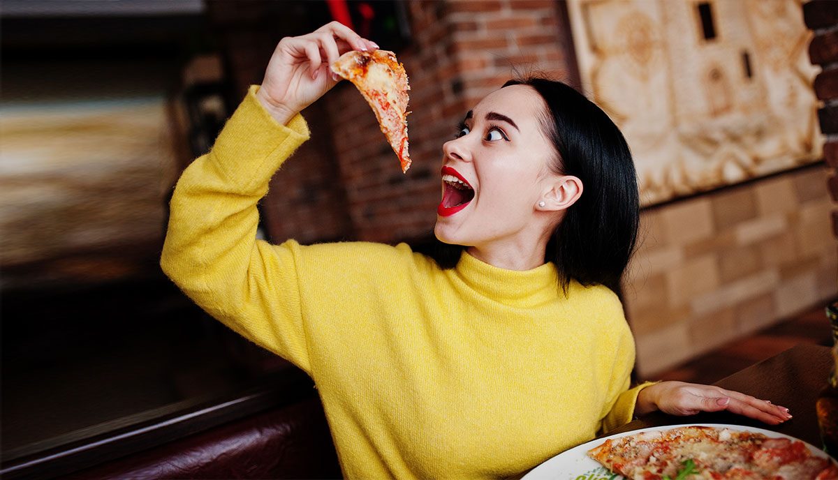 Девушка ест пиццу в ресторане